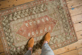 Distressed Melas rug with terra cotta field, faded roses, and olive green border.