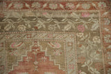 Distressed hand-knotted Melas corner showing stepped spandrels, terra cotta and pink florals.
