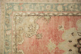 Vintage distressed Oushak rug corner, dusty blush field, slate blue Rococo outlines.