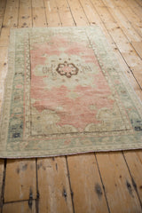 Distressed vintage Oushak rug corner, showing blush field, slate blue border, and faint foundation.