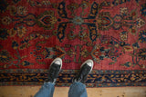 Nuanced floral patterns with serrated leaves and palmettes on the deep ruby red field of an antique Sarouk.