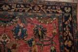 Intricate border detail on an antique Persian Sarouk with serrated leaves in deep teal and gold on raspberry.