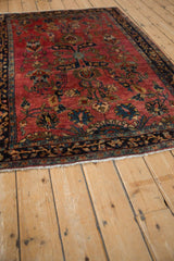 Angled perspective of a fine Persian Sarouk rug, detailing its rich ruby-red field and complex floral pattern.