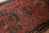 Angled view of an antique Sarouk's low pile, showing serrated floral leaves and visible knot heads.