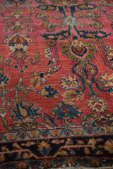 Angled view across the antique Sarouk rug's short pile showing detailed palmettes.