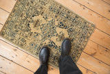 Antique Tabriz rug mat on a wood floor with feet for a sense of scale.