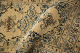 A folded antique Tabriz rug showing its low, dense wool pile and intricate sapphire floral motifs.