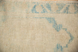 Close-up of distressed ivory and sky blue Oushak rug pile with heavy abrashes.