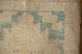 Distressed Oushak rug pile close-up: ivory and sky blue pattern with mostly even wear.