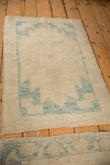 Distressed Oushak runner with sky blue geometric border and worn ivory pile texture.