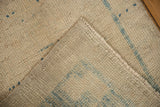 Close-up of distressed Oushak rug with textured pile, intact selvage, and blue woven foundation.