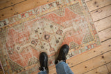 Faded dusty blush and mint green patterns on a distressed vintage Oushak rug.