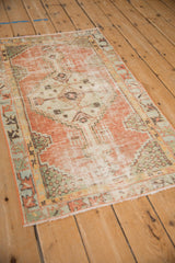 Distressed corner and stepped border of a vintage Oushak rug with blush, ivory, and green.