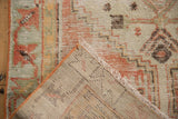 Vintage Distressed Oushak rug corner, showing machine-bound side, fringe, and muted pile pattern.