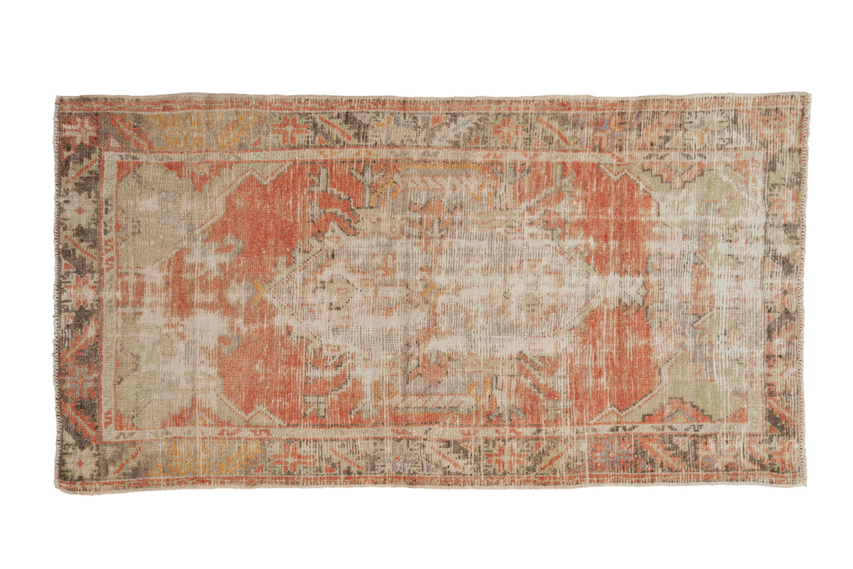 Distressed vintage Oushak rug with a shield medallion in dusty blush, silver, and mint green.
