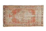 Distressed vintage Oushak rug with a shield medallion in dusty blush, silver, and mint green.