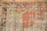 Corner of a distressed Turkish Oushak rug with low-worn pile and visible foundation.