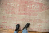 The textured short pile and pink abrash color variations of a distressed vintage Oushak carpet.