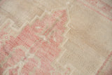 Close-up of the distressed, short pile and pink diamond floral motif on an ivory Oushak.