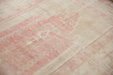 Faded pink geometric motifs and ivory abrashes on the distressed short pile of a vintage Oushak.