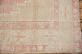 The decorative short pile and soft pink geometric border of a distressed vintage Oushak carpet.