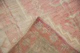 Folded corner of a vintage Oushak rug revealing its hand-knotted pink and beige foundation.
