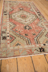 Distressed pile of the Oushak runner, showing dusty rose and seafoam green with geometric arrow patterns.