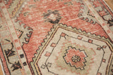 Close-up of distressed vintage Oushak runner featuring dusty rose, seafoam, and ivory patterns.