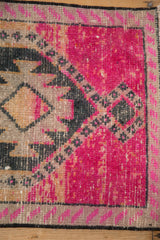 Low pile texture on a distressed Kars rug corner with fuchsia and charcoal geometric details.