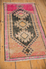 Angled view of a distressed Kars runner's serrated charcoal medallions and vibrant fuchsia accents.