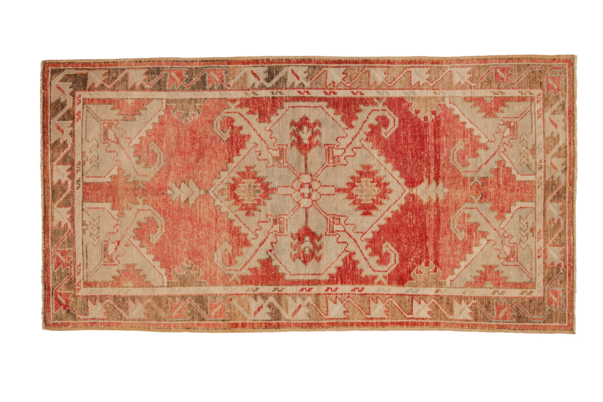 Vintage distressed Oushak rug runner with a central diamond medallion in blush, pale red, and bronze tones.