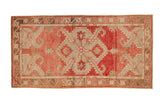 Vintage distressed Oushak rug runner with a central diamond medallion in blush, pale red, and bronze tones.