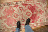 Looking down at a vintage Oushak runner's faded blush-red pattern and distressed texture.