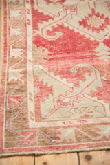 Detail of the worn, low pile and primitive vine border in blush and coffee brown on a vintage Oushak.