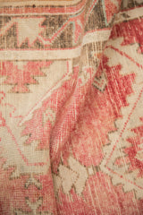 A soft fold in the distressed Turkish Oushak shows the hand-knotted texture in blush and bronze.