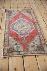 A high-angle view of the vintage Oushak mat, showcasing its distressed red field and central blue medallion.