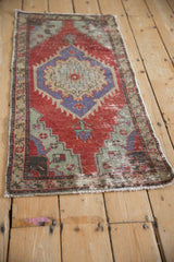 Angled view of a vintage distressed Oushak mat highlighting its worn pile and central medallion design.