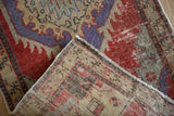 Folded corner of a distressed Oushak rug showing its low pile and hand-knotted foundation.