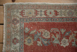 Distressed Oushak rug with brick red floral field and dusty blue serrated leaf border.