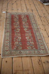 Distressed brick red Oushak runner with dusty blue floral sprays, white knots, and serrated leaf border.