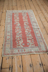 Distressed brick red field with faded blue and ivory floral spray motifs.