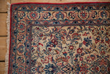 Fine floral border and red selvage on a vintage Isfahan rug corner with short cream fringe.