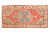 Vintage distressed Oushak rug with a blue hexagonal medallion on a faded cherry red field with mint accents.