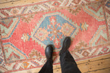 Distressed vintage Oushak rug with red and blue medallion shown underfoot to display texture and scale.
