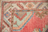 Corner detail of a distressed Oushak rug with a serrated leaf border and geometric spandrel.