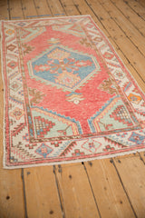 Angled view of the distressed Oushak rug highlighting its hexagonal medallion and soft cherry red field.
