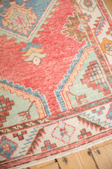 Corner of a distressed Oushak showing serrated spandrels and a pinwheel blossom border.