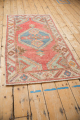 Angled view of a vintage distressed Oushak rug with its geometric blue medallion and red field.