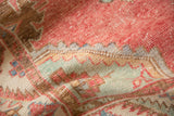 Detail of the distressed Oushak rug's low-pile texture and serrated motifs in red and mint green.