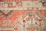Worn texture of a vintage Oushak rug's stepped medallion with geometric floral blossoms in madder red.